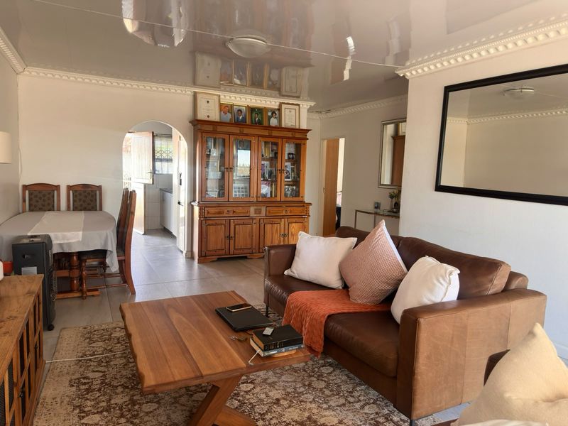 Open plan living and dining area featuring a glossy ceiling, decorative cornice, and tiled flooring with an arched entryway leading to the kitchen.