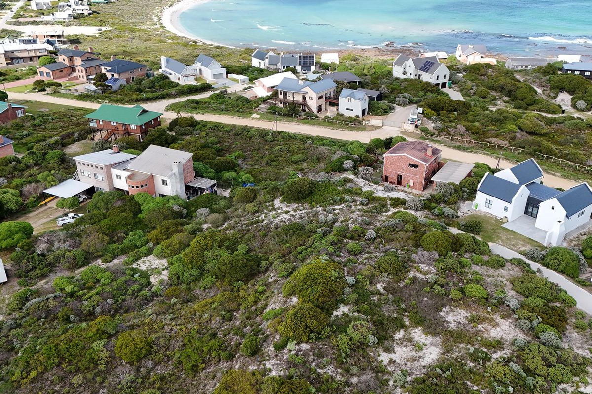An aerial view of a coastal residential neighborhood featuring established homes, natural vegetation, and proximity to the ocean.