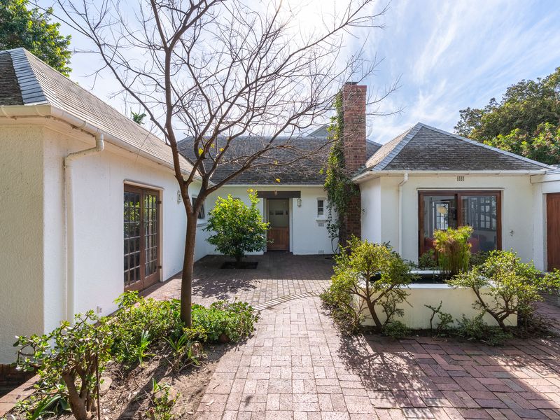 A charming rear courtyard featuring brick paving, a masonry planter box, and direct access to the home through timber-framed glass doors.
