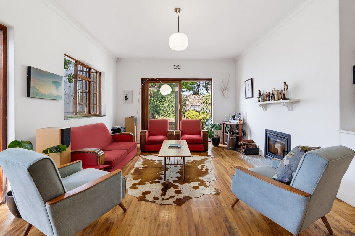 A bright living room featuring polished hardwood floors, a built-in fireplace, and large sliding glass doors providing direct access to the garden.