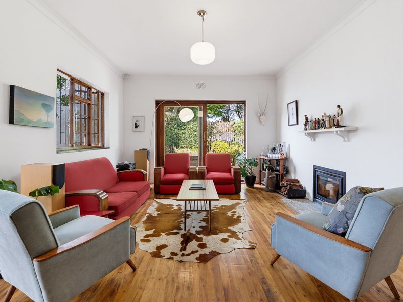 A bright living room featuring polished hardwood floors, a built-in fireplace, and large sliding glass doors providing direct access to the garden.
