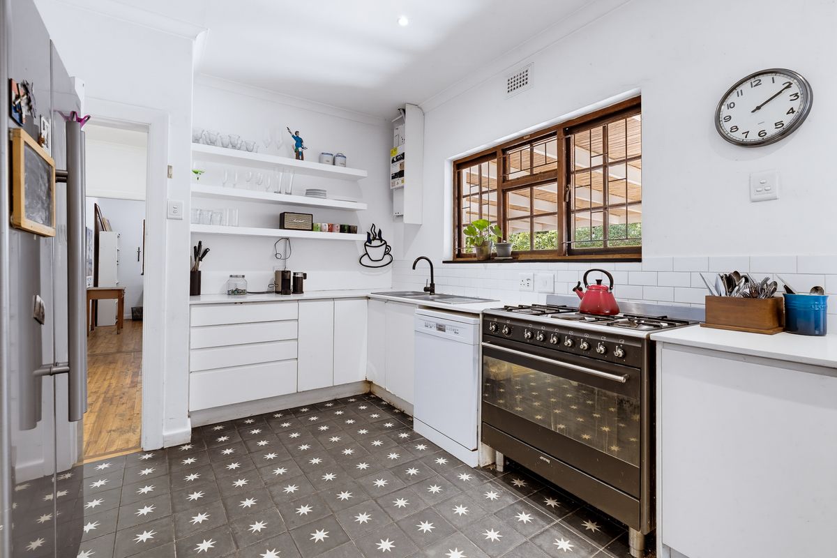 A bright kitchen featuring a gas stove, subway tile backsplash, built-in shelving, and patterned floor tiles, offering a functional and well-maintained workspace.