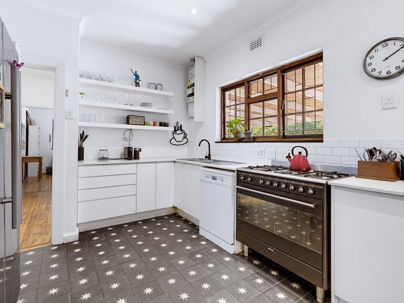 A bright kitchen featuring a gas stove, subway tile backsplash, built-in shelving, and patterned floor tiles, offering a functional and well-maintained workspace.