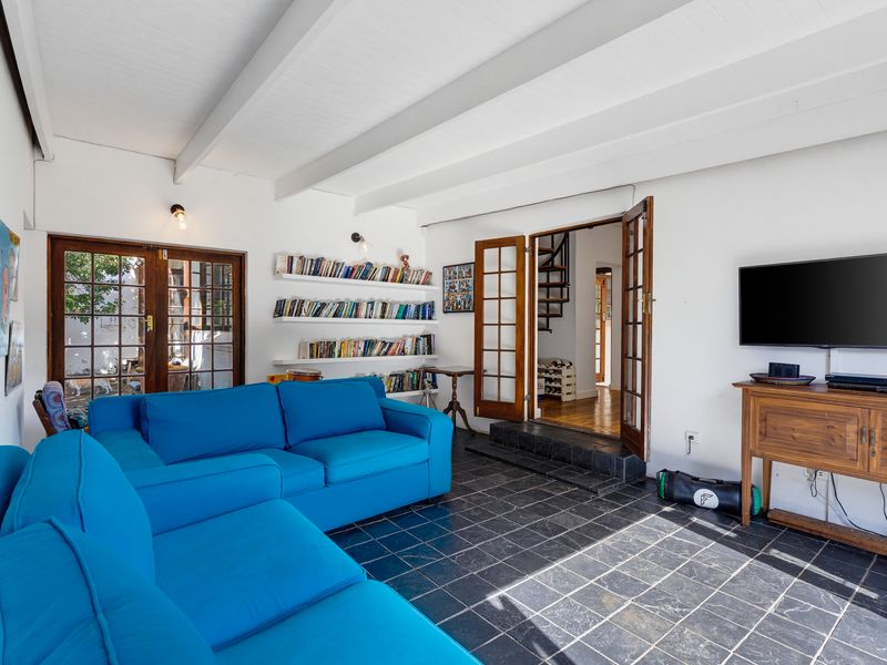 A bright living room featuring slate tile flooring, exposed beam ceilings, and double french doors leading to an adjacent space.