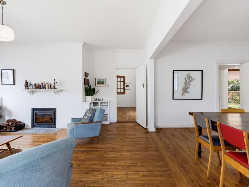 Spacious open-plan living and dining area featuring polished hardwood flooring, a built-in fireplace, and classic architectural detailing.