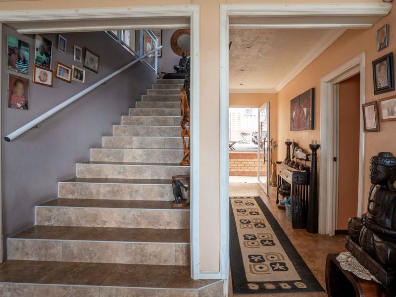 A tiled staircase and hallway area leading to an exterior doorway, featuring neutral wall tones and built-in structural transitions.