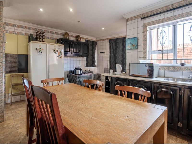 A functional kitchen featuring built-in cabinetry, tiled backsplash, and a stainless steel sink, offering potential for modernization and aesthetic updates.