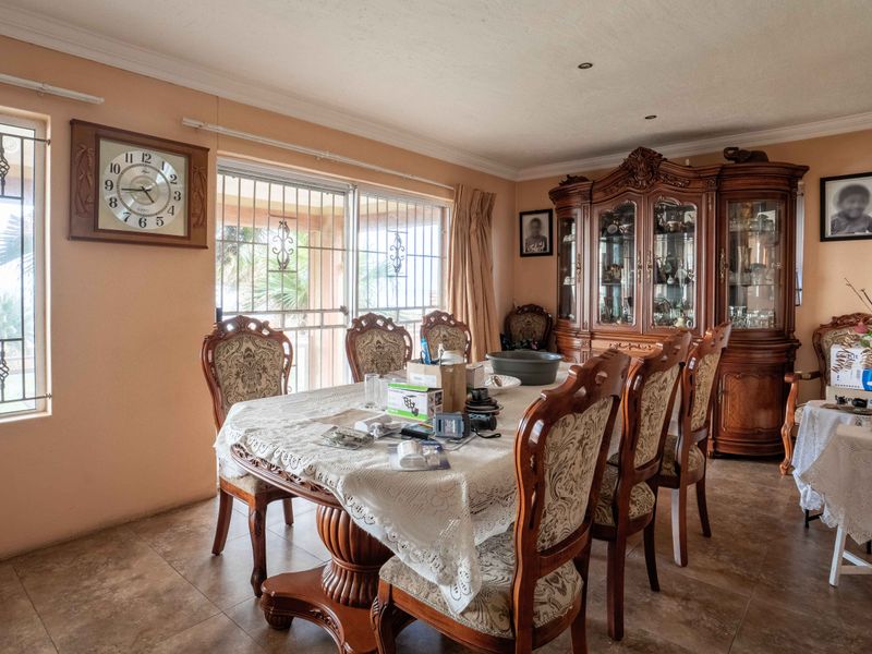 A traditional dining room featuring tiled flooring, coving, and a sliding glass door with security bars, providing access to the exterior.