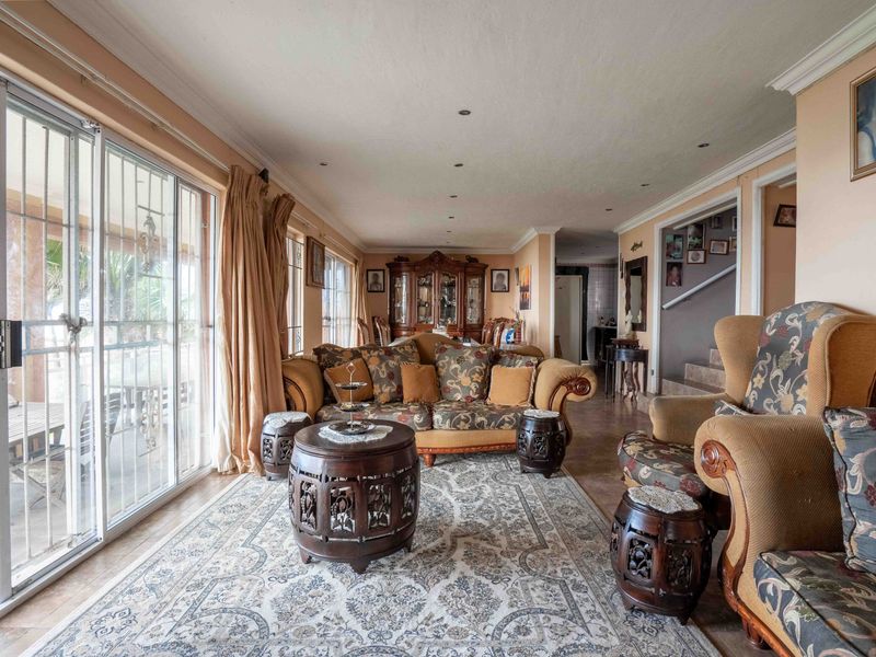 Spacious living room featuring tiled flooring, recessed lighting, and large sliding glass doors with security bars providing access to the outdoor area.