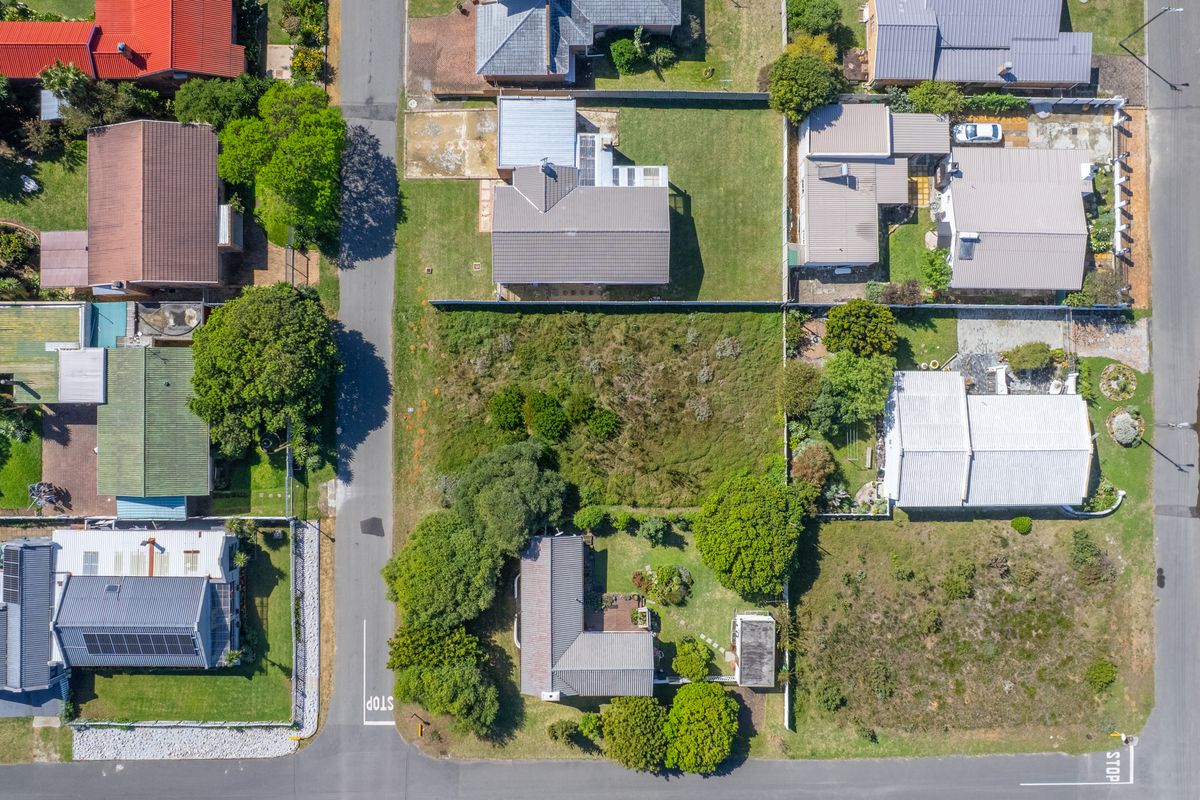 An aerial view of a vacant residential plot situated within an established suburban neighborhood, offering potential for new development.