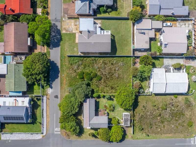 An aerial view of a vacant residential plot situated within an established suburban neighborhood, offering potential for new development.