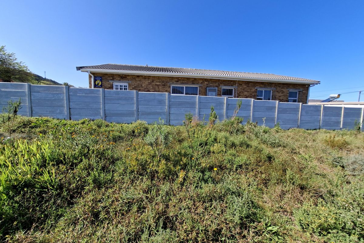 View of the rear exterior of the residential property, featuring a facebrick facade, tiled roof, and a precast concrete boundary wall.