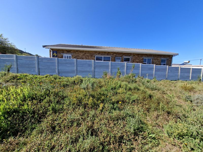 View of the rear exterior of the residential property, featuring a facebrick facade, tiled roof, and a precast concrete boundary wall.