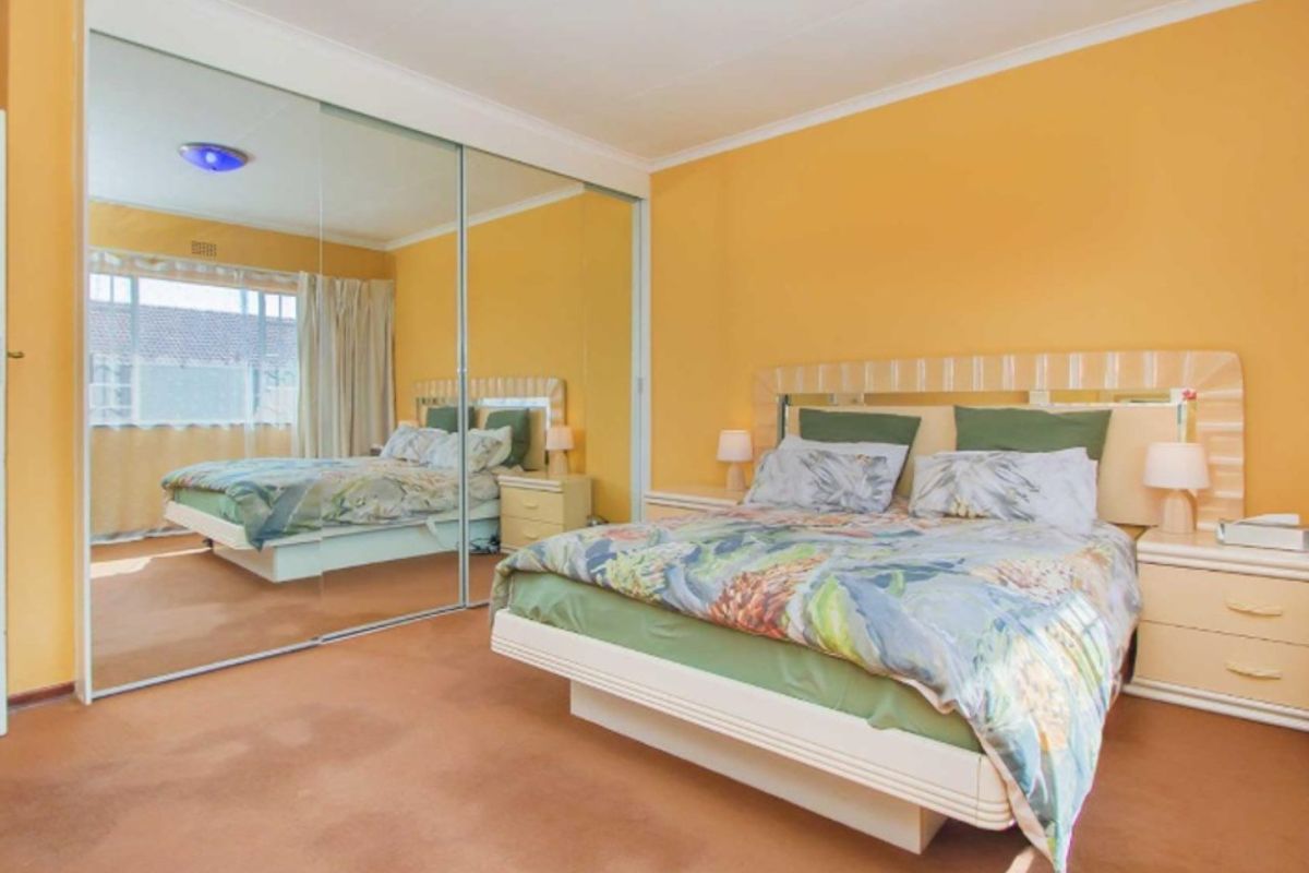 A bedroom featuring a large built-in mirrored wardrobe, carpeted flooring, and a sliding window with natural light.