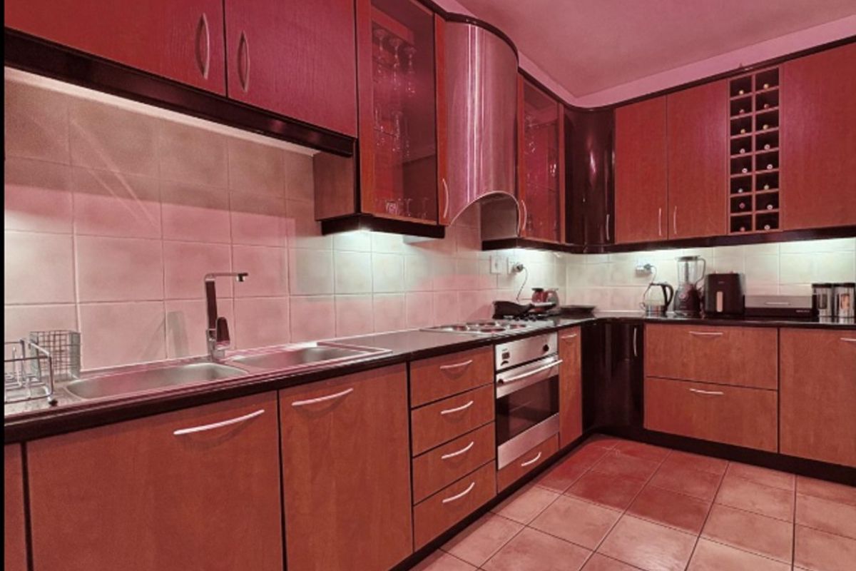 A functional kitchen featuring wood-tone cabinetry, integrated appliances, a tiled backsplash, and a dedicated wine rack, offering ample storage and workspace.