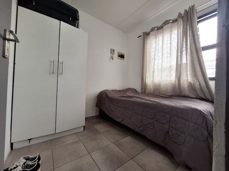 A compact bedroom featuring tiled flooring and a built-in wardrobe, providing functional storage space.