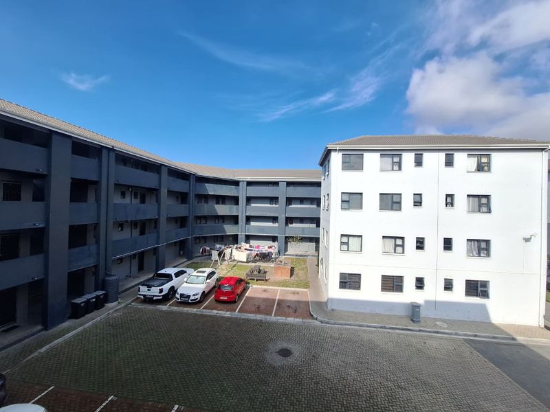 An elevated view of the apartment complex courtyard featuring paved parking areas and multi-story residential building facades.