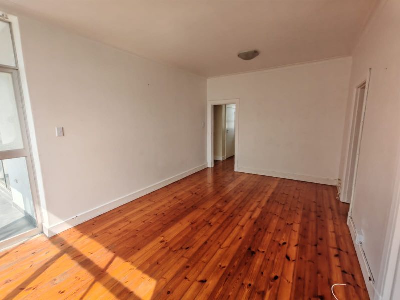 A bright, empty living room featuring polished timber flooring and neutral walls, offering a blank canvas for interior design.