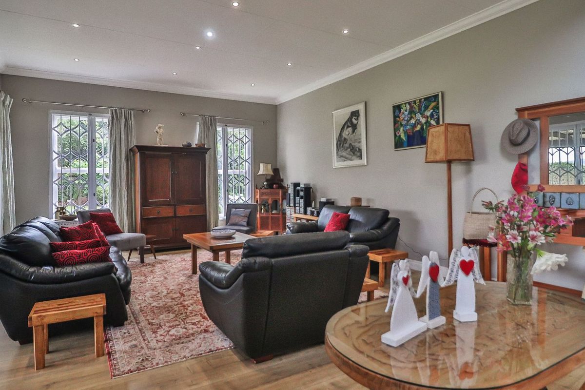 Spacious living room featuring laminate flooring, recessed downlighting, and large windows with security bars, offering a comfortable and well-maintained living space.