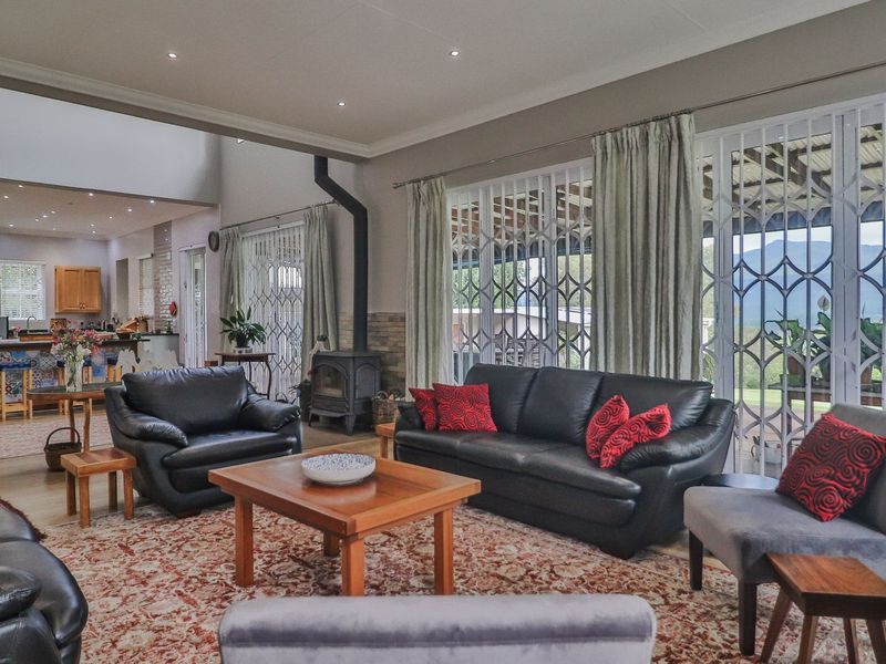 Spacious open-plan living area featuring a freestanding fireplace, recessed lighting, and large sliding doors leading to an outdoor patio with mountain views.