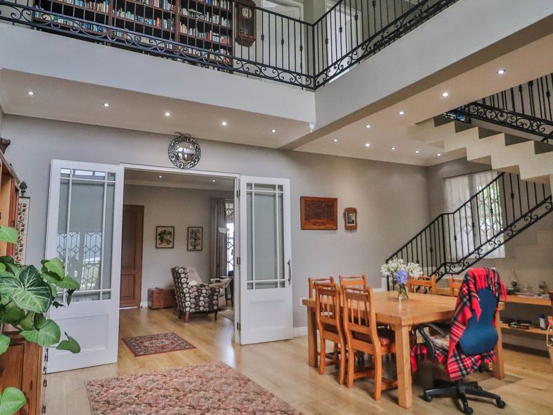 Spacious living area featuring a double-volume ceiling, a mezzanine library with wrought iron railings, and a staircase leading to the upper level.