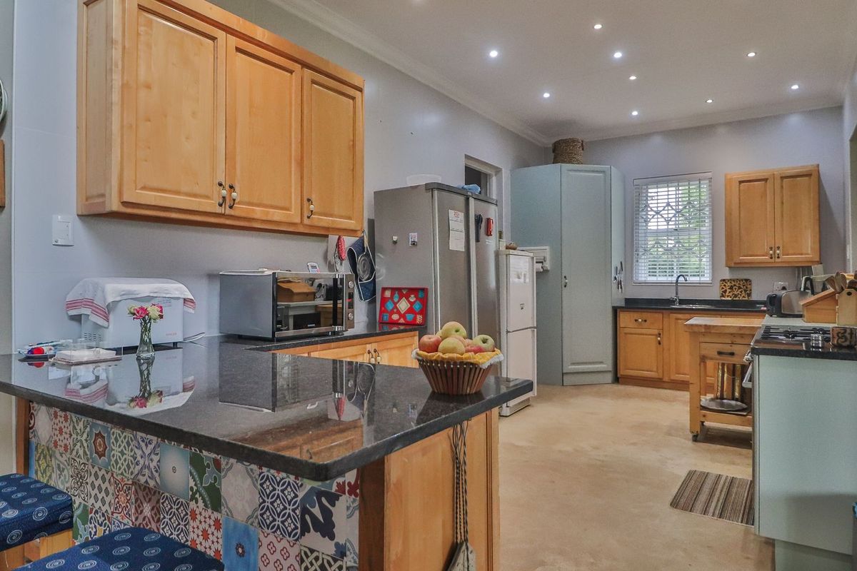 Spacious kitchen featuring wooden cabinetry, granite countertops, a decorative tiled island, and recessed lighting, offering a functional layout with ample storage space.