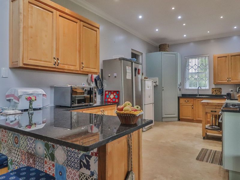 Spacious kitchen featuring wooden cabinetry, granite countertops, a decorative tiled island, and recessed lighting, offering a functional layout with ample storage space.