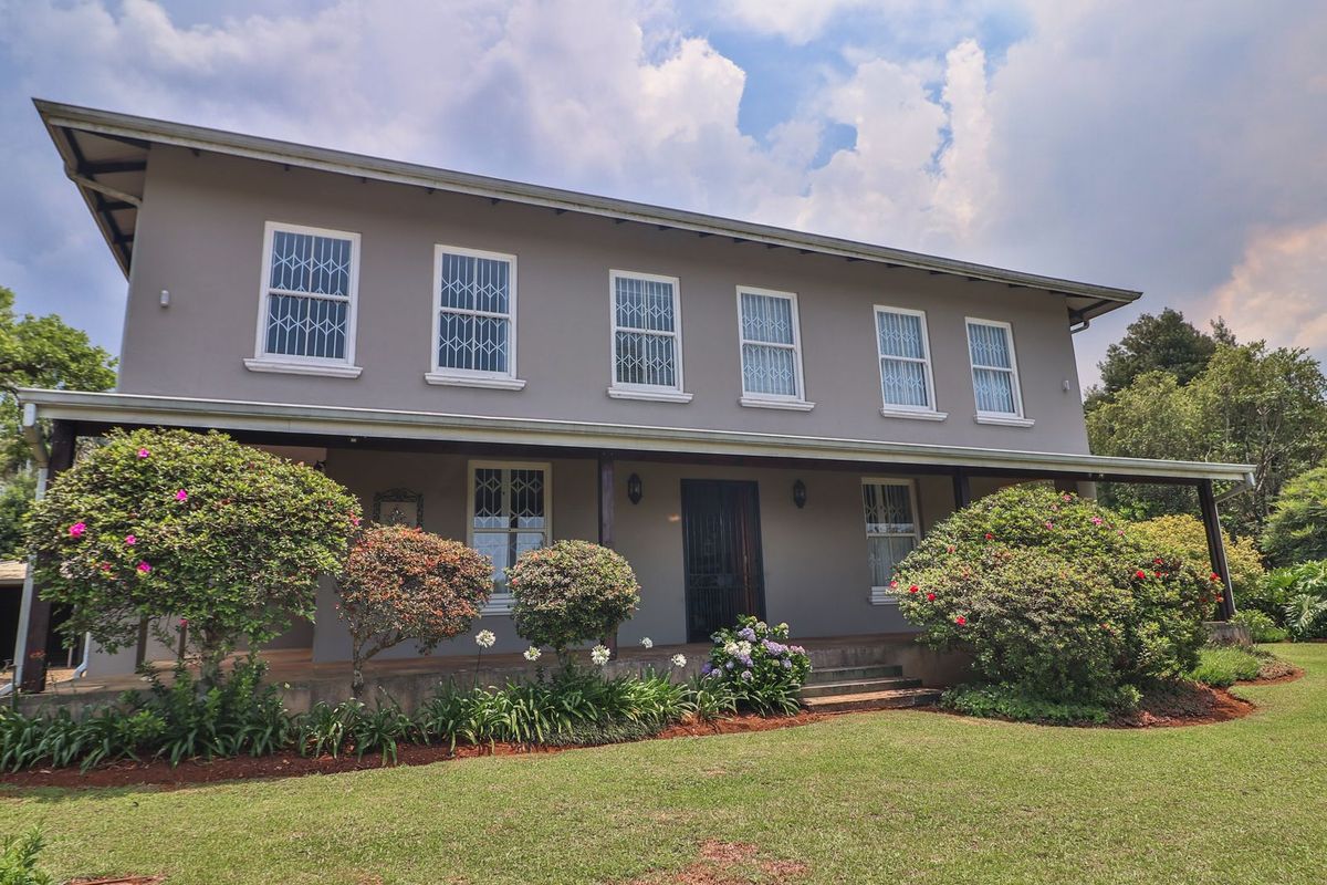 A well-maintained two-story house featuring a covered patio, security-fitted windows, and a spacious, established garden.