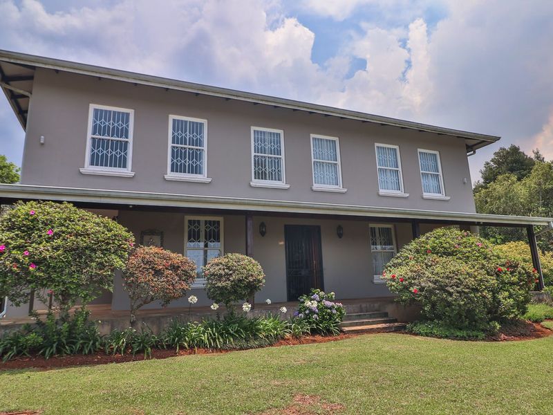 A well-maintained two-story house featuring a covered patio, security-fitted windows, and a spacious, established garden.