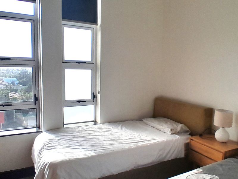 A bedroom featuring built-in wardrobes and large windows providing natural light and an elevated view.