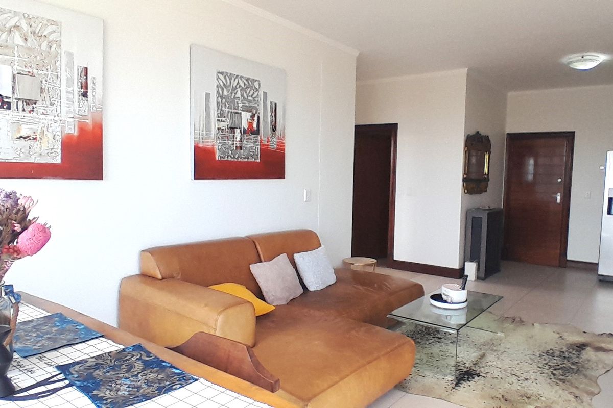 An open-plan living area featuring neutral tiled flooring, solid core doors, and a functional layout suitable for modern apartment living.