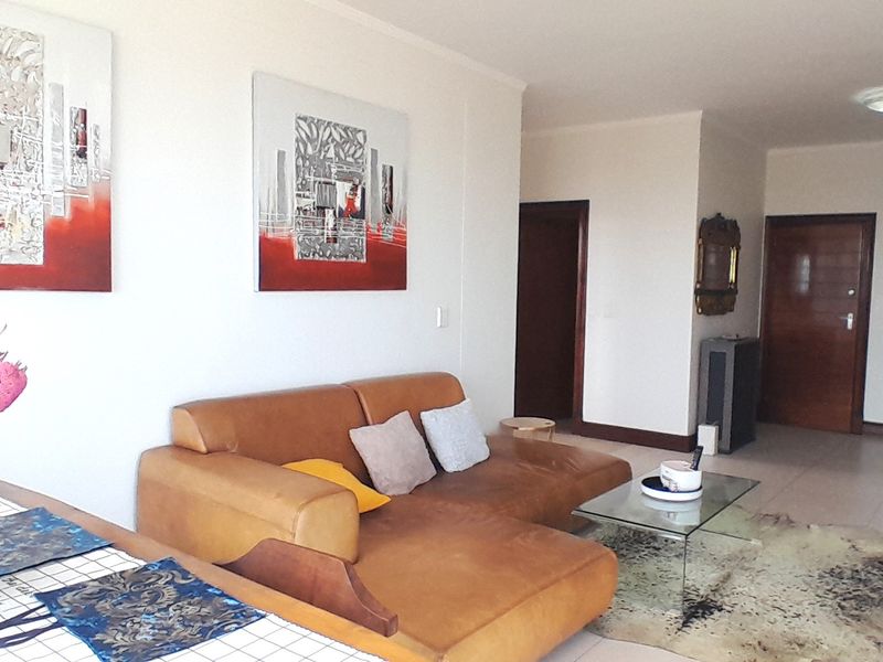 An open-plan living area featuring neutral tiled flooring, solid core doors, and a functional layout suitable for modern apartment living.