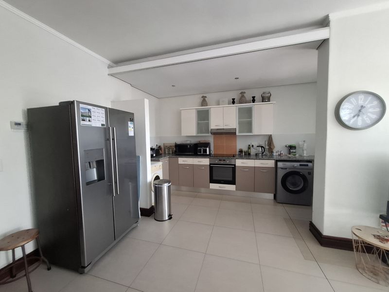 A functional kitchen featuring two-tone cabinetry, stone countertops, integrated oven and hob, and tiled flooring, providing a practical workspace for daily cooking.