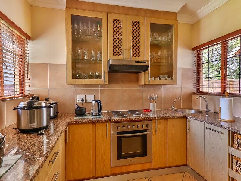 A functional kitchen featuring wooden cabinetry, granite countertops, a built-in oven with hob, and a tiled backsplash, offering a classic and practical workspace.