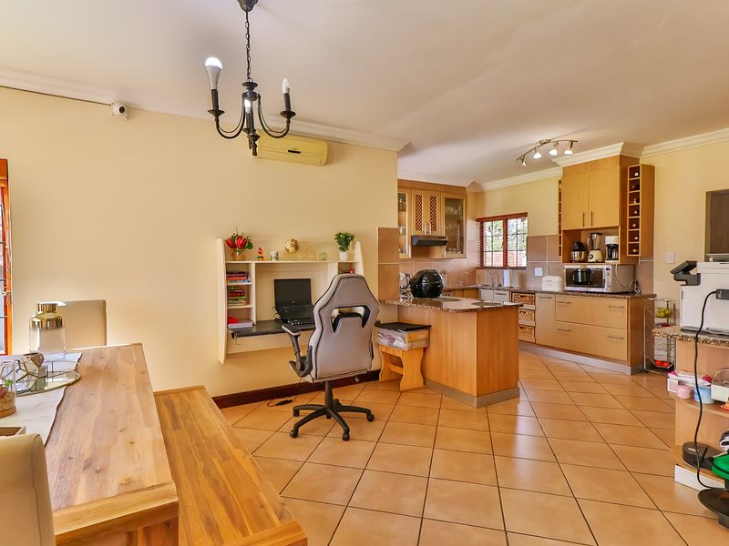 Open-plan living and kitchen area featuring tiled floors, wooden cabinetry, granite countertops, and a built-in workspace, offering a functional and connected layout.