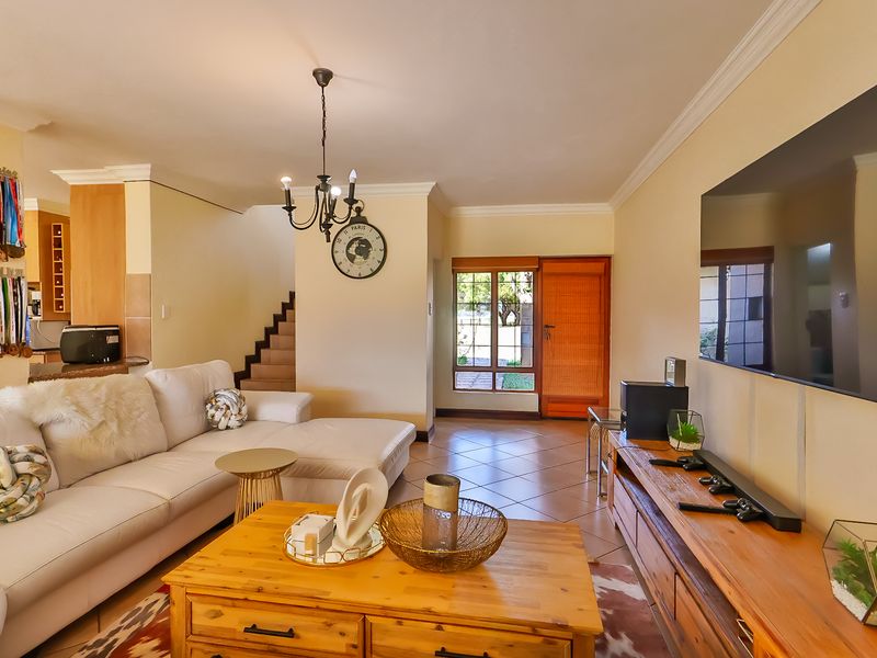 Open-plan living area featuring tiled flooring, cove cornicing, and a staircase, seamlessly connecting to the kitchen space.