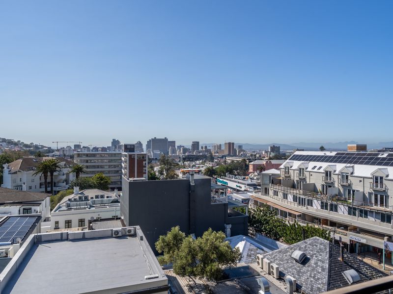 Elevated urban cityscape view overlooking surrounding apartment buildings and rooftops under a clear blue sky.