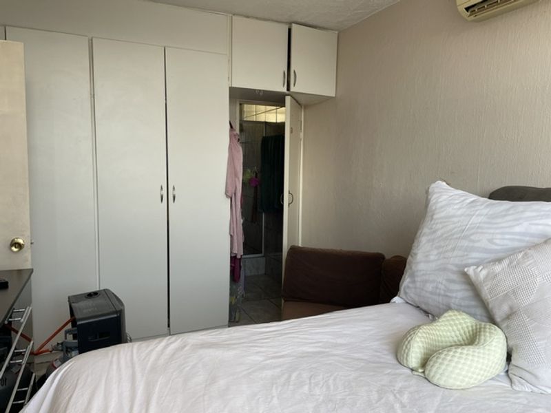 Bedroom featuring built-in cupboards with overhead storage and a wall-mounted air conditioning unit, providing functional storage and climate control.