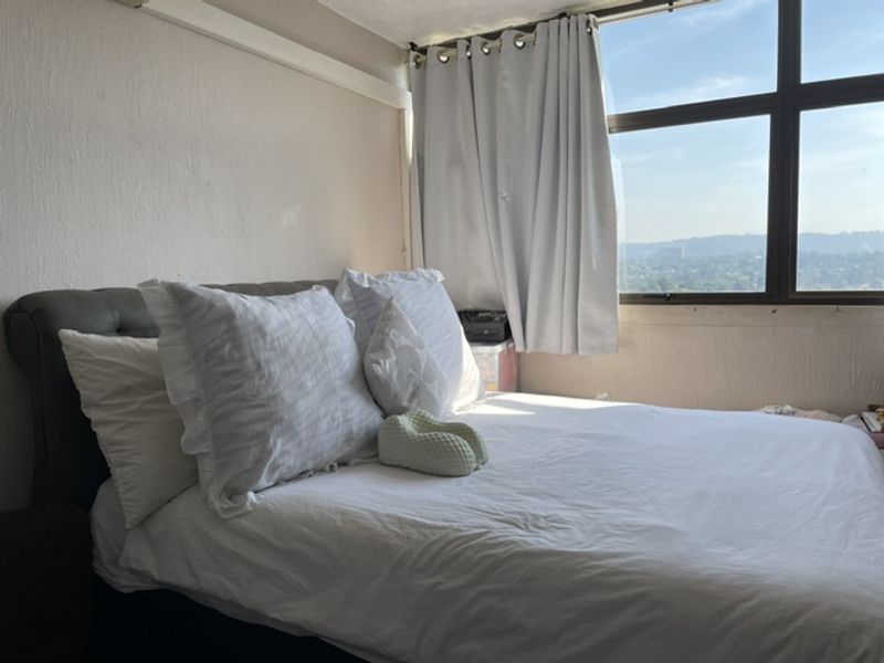 A bedroom featuring a large window with natural light and elevated views, providing a bright and airy atmosphere.