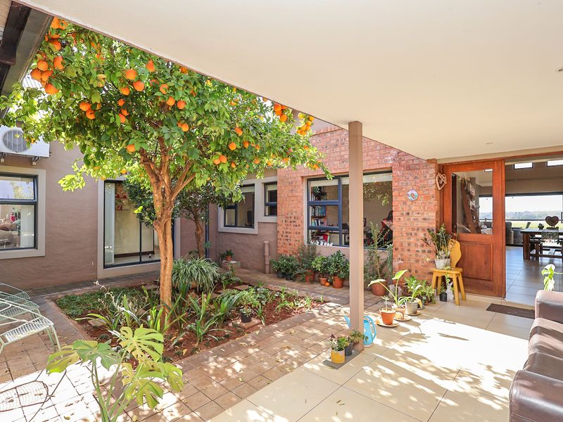 A covered patio area featuring tiled flooring and exposed brickwork, providing a seamless transition between the indoor living space and the central garden courtyard.