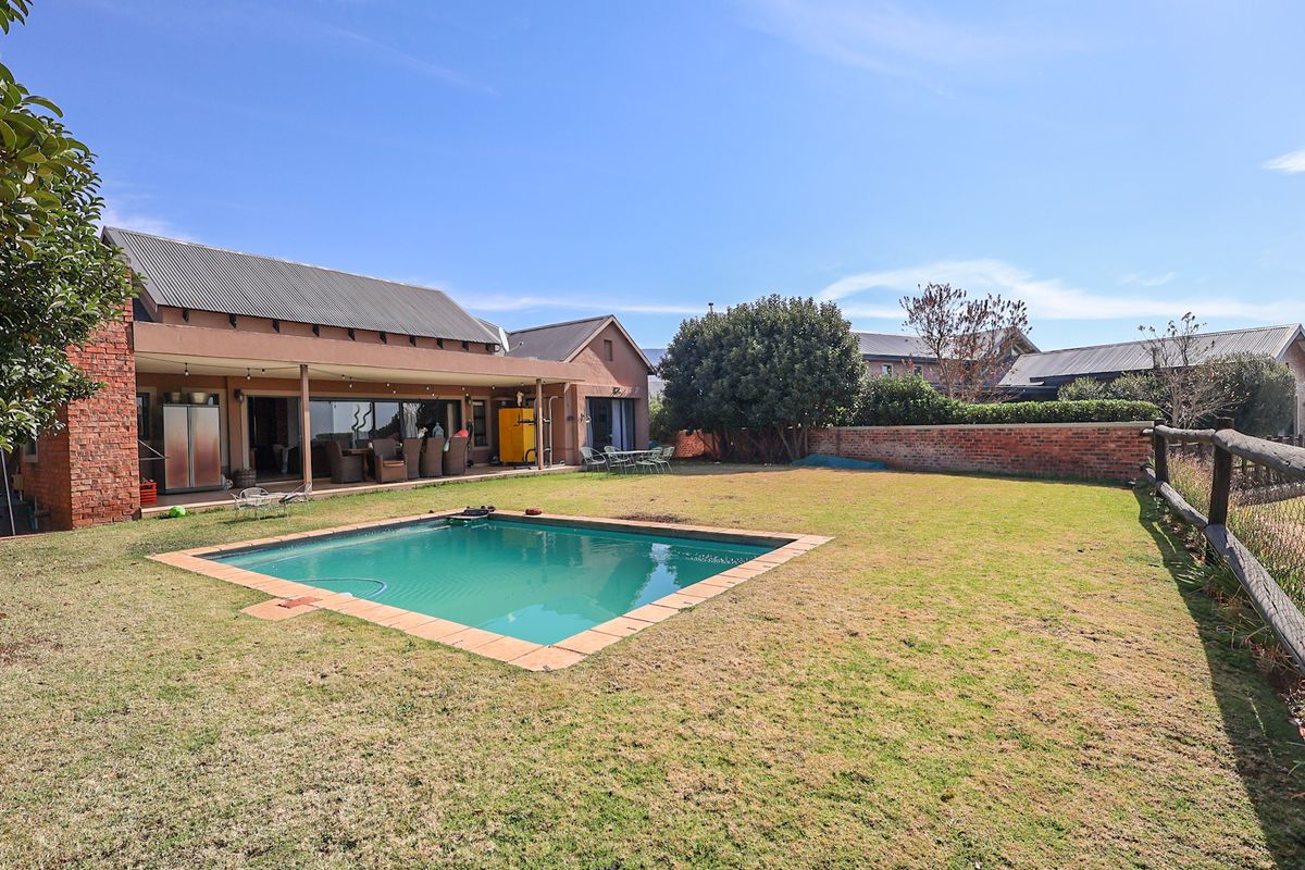 Spacious rear garden featuring a swimming pool, covered patio area, and established brick boundary walls, offering a private outdoor living space.