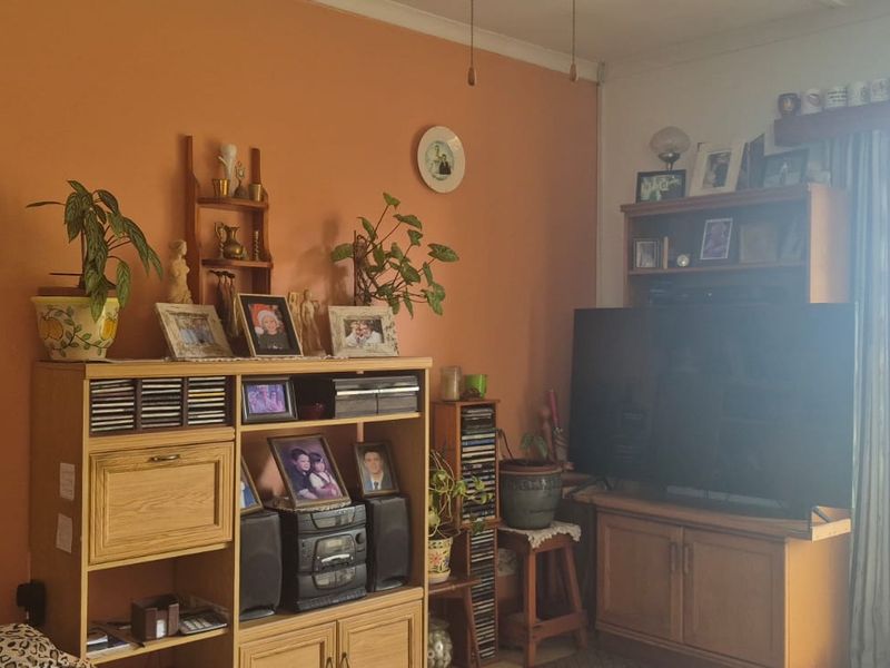 A living room featuring a sliding glass door providing access to the garden, with orange painted walls and traditional coving.