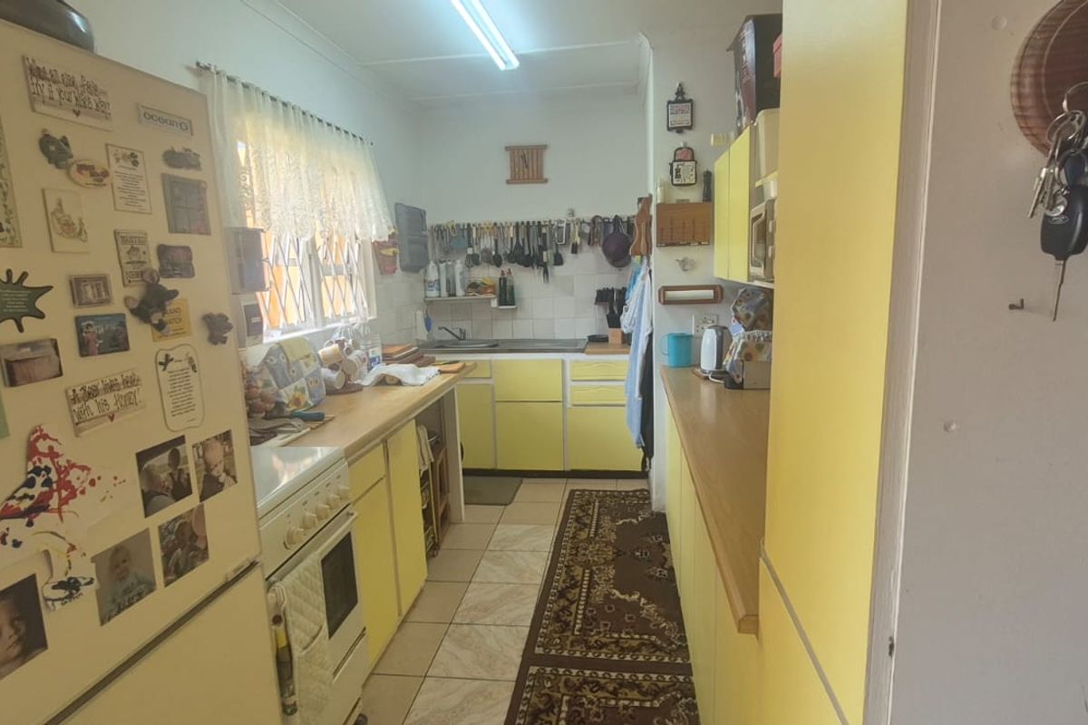 A functional kitchen featuring yellow cabinetry, laminate countertops, a freestanding stove, and tiled flooring, offering a classic layout with ample storage space.
