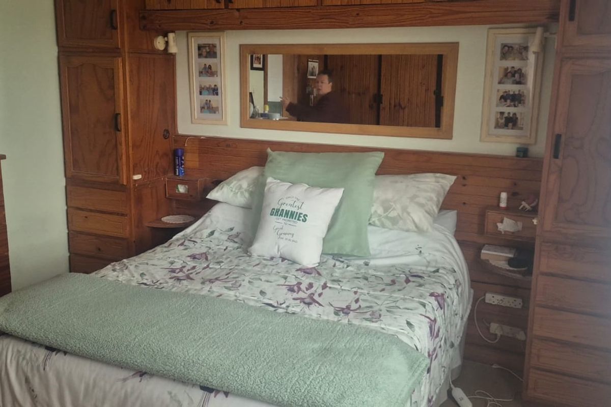 A bedroom featuring extensive built-in wooden cabinetry and an integrated headboard with a central mirror.
