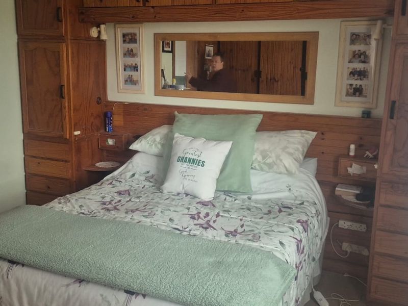 A bedroom featuring extensive built-in wooden cabinetry and an integrated headboard with a central mirror.