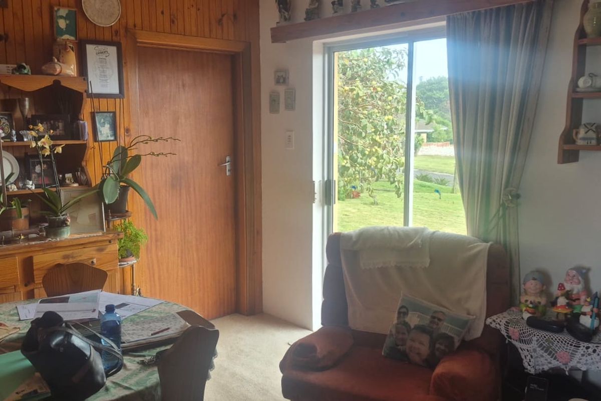 A living area featuring timber wall paneling, carpet flooring, and a sliding glass door providing access to the garden.