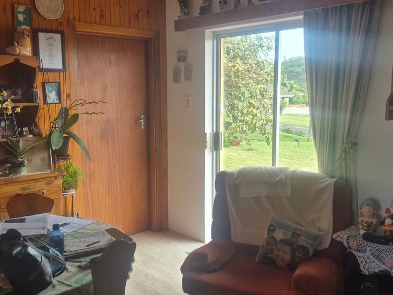 A living area featuring timber wall paneling, carpet flooring, and a sliding glass door providing access to the garden.