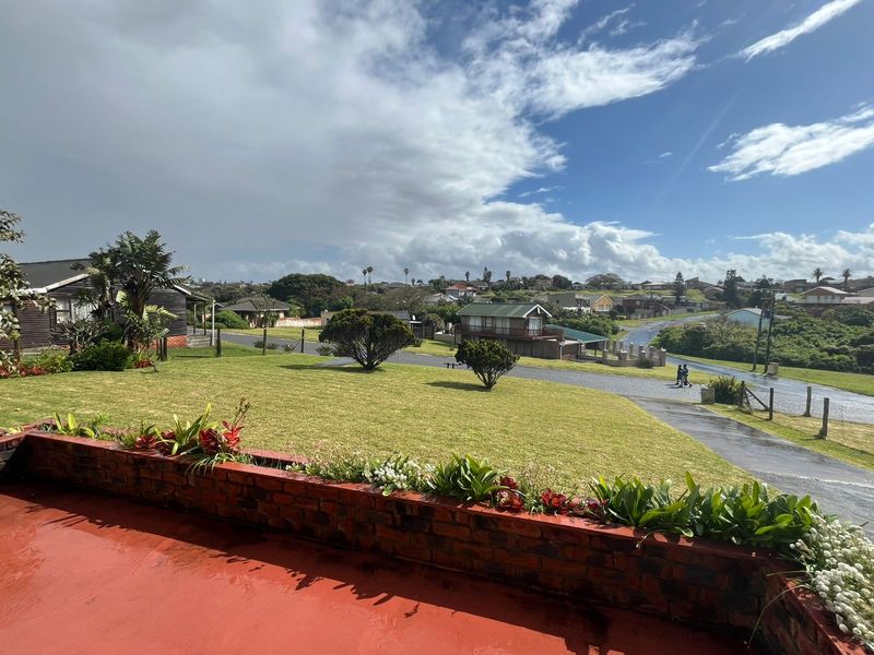 Elevated view overlooking the surrounding residential neighbourhood and green landscape from a brick-bordered patio area.