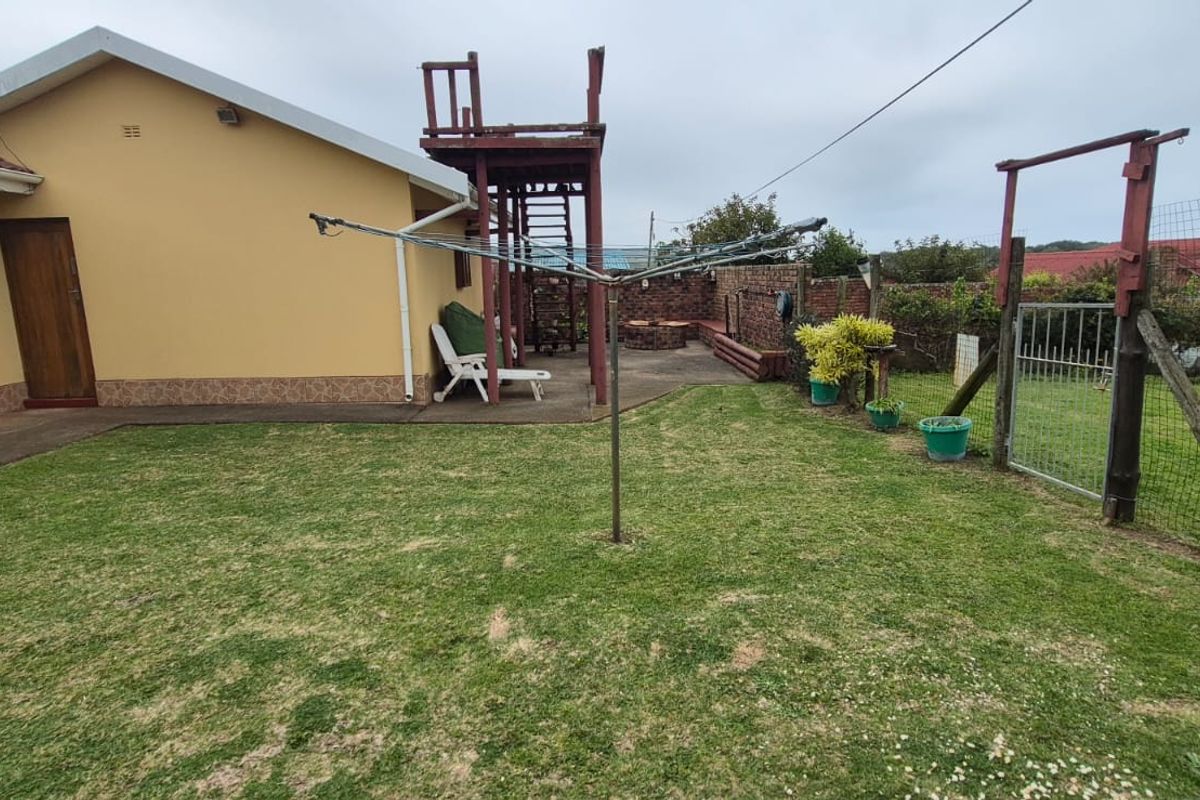 Rear exterior view of the property featuring a concrete patio, lawn area, and a raised wooden viewing platform with perimeter fencing.