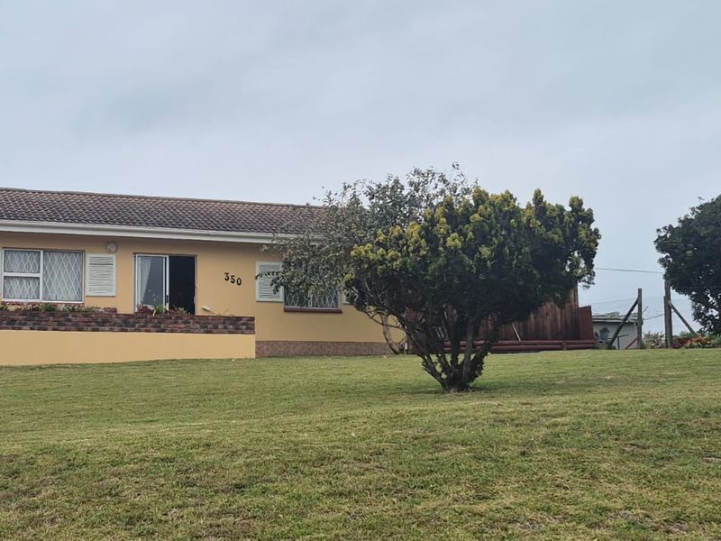 Front view of a single-story residential house featuring a tiled roof, attached garage, and a large front lawn with established landscaping.